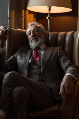 Tatmin olmuş sakallı bir emeklinin evinde dinlenirken gözlük takması..