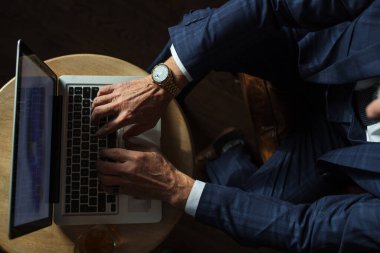 Dizüstü bilgisayara bakan, barda otururken roman yaratan kıdemli bir tiyatrocu..