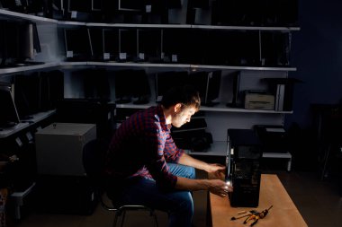 hardworking IT specialist working with a computer in the dark room at night clipart