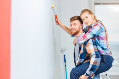 Genç çift yeni evlerinde duvar boyuyor, sırtına biniyor ve eğleniyor..