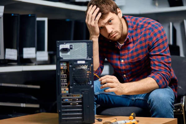 IT-technicus houdt zijn voorhoofd vast en repareert gebroken pc-computer — Stockfoto