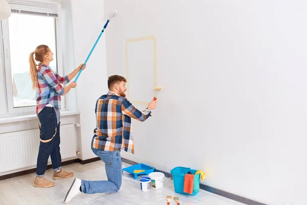 Team junger Maler in karierter Kleidung mit Walzen, die drinnen arbeiten — Stockfoto