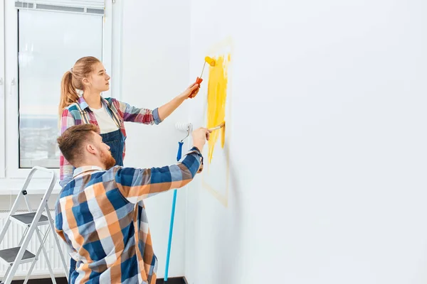 Gelukkig paar hebben plezier renoveren hun nieuwe huis samen met behulp van op een roller — Stockfoto