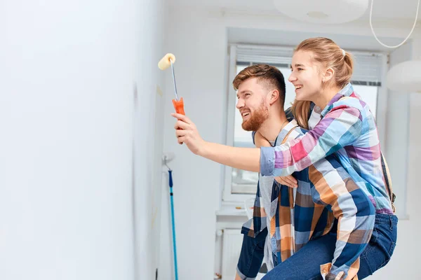 Junges Paar streicht Wände und hat Spaß im neuen Haus. — Stockfoto