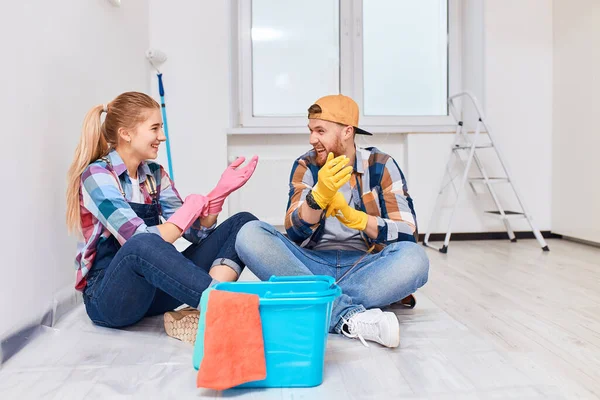 Paar klaar om te schilderen, zitten op de vloer, het aantrekken van rubberen handschoenen — Stockfoto