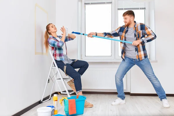 Equipo de jóvenes pintores en ropa a cuadros con rodillos trabajando en interiores —  Fotos de Stock