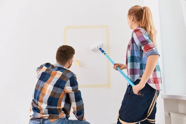 하얀 벽에 롤러를 사용하여 새 집을 수리하는 행복 한 부부 — 스톡 사진