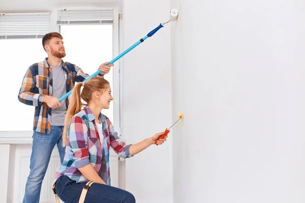 하얀 벽에 롤러를 사용하여 새 집을 수리하는 행복 한 부부 — 스톡 사진