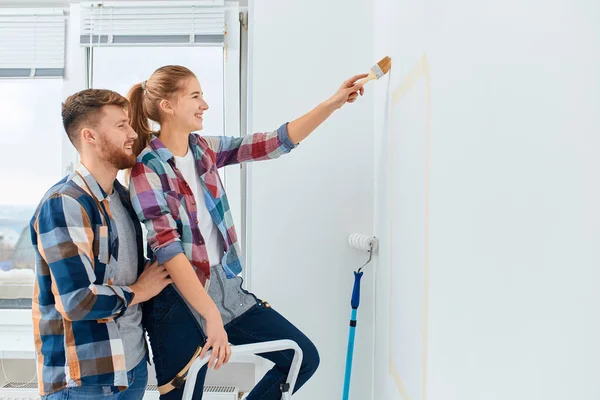 Couple heureux s'amuser à rénover leur nouvelle maison ensemble en utilisant un rouleau — Photo