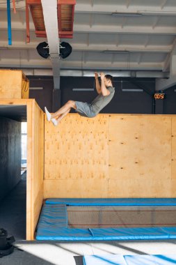 Spor salonunun duvarına tırmanan genç aktif bir adam.