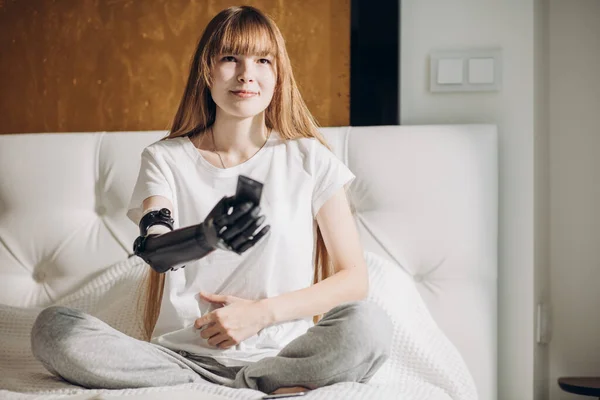 Attraktives Mädchen mit künstlichem Arm schaltet den Fernseher ein — Stockfoto