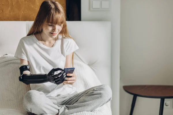 Happy girl with artificial arm sending messages, sms — Stock Photo, Image