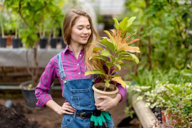 Çiçek saksısı olan mutlu sarışın kadın bahçıvan.