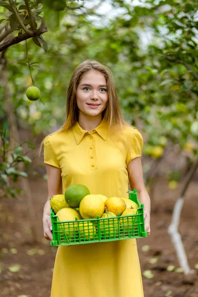 Encantadora mujer jardinero con limones mirando a la cámara — Foto de Stock