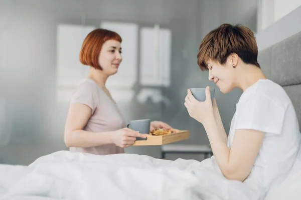 Pleasant girl brings hot green tea for a girlfriend — Stock Photo, Image