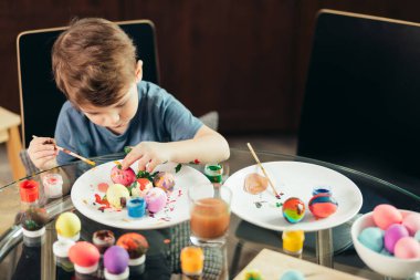 Mutlu küçük çocuk Paskalya yumurtaları, çocuklar ve yaratıcılık çiziyor.