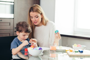 Mutlu Paskalyalar. Genç anne ve küçük oğlu Paskalya yumurtası boyuyor..