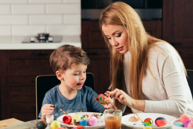 Mutlu Paskalyalar. Genç anne ve küçük oğlu Paskalya yumurtası boyuyor..