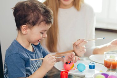 Mutlu Paskalyalar. Genç anne ve küçük oğlu Paskalya yumurtası boyuyor..