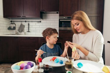 Mutlu Paskalyalar. Genç anne ve küçük oğlu Paskalya yumurtası boyuyor..