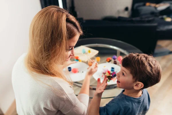 Feliz Pascua Joven madre y su pequeño hijo pintando huevos de Pascua. — Foto de Stock