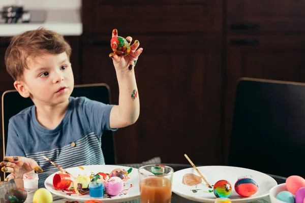 Happy little boy painting Easter eggs, children and creativity
