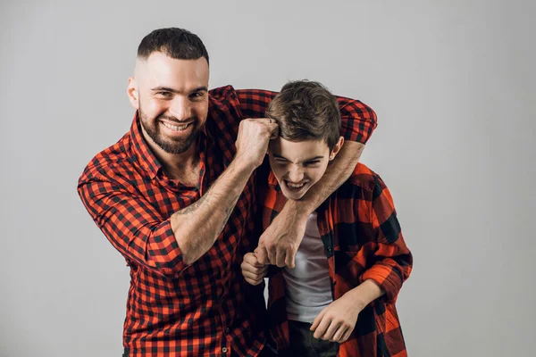 Vicces szakállas apa és a fia harcolnak a szürke háttér — Stock Fotó