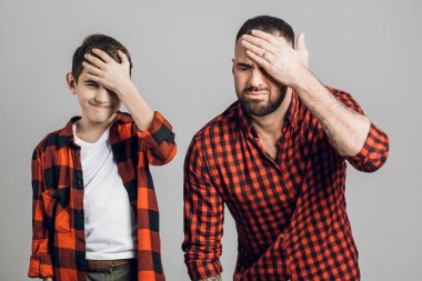 Yakışıklı genç adam ve çocuğunun başı ağrıyor. Gri arkaplanda izole.