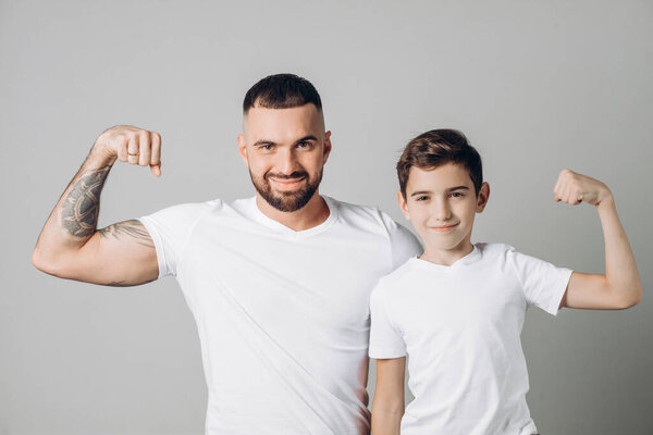 positive man and little boy with raised arms are posing to the camera