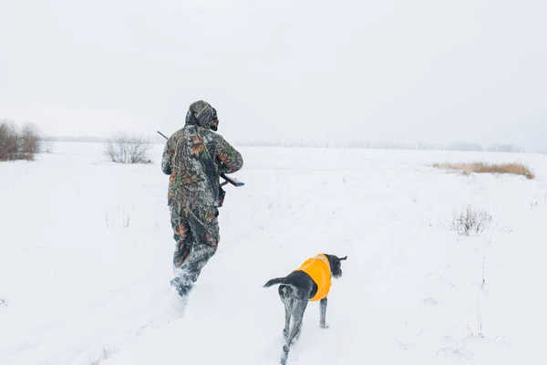 Cazador y perro caminando en el campo cubierto de nieve — Foto de Stock