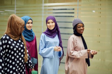 Çok ırklı dört Müslüman kızdan oluşan bir grup sohbet ediyor ve birlikte yürüyorlar.