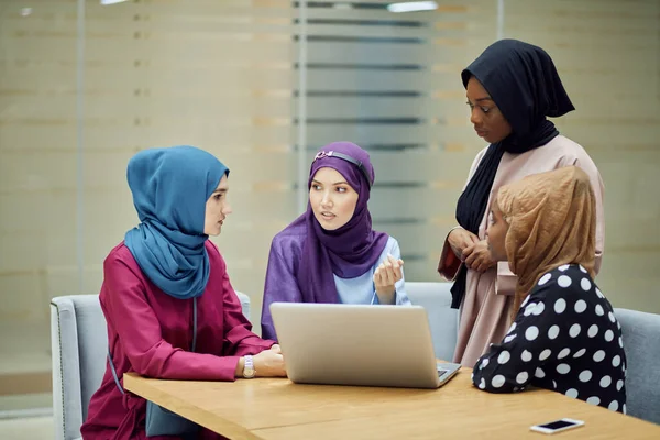 Musulmán asiático y africano mujeres en la cabeza bufandas y hijab utilizando el ordenador portátil en la cafetería — Foto de Stock