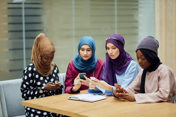 Arabian young women watching on cellphone musical video clip standing together. — Stock Photo, Image