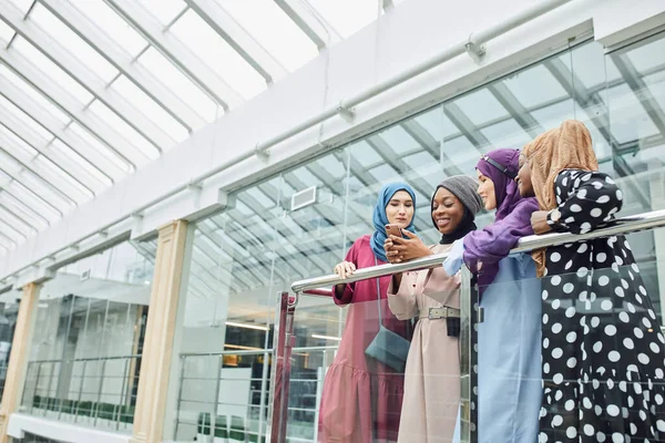 Grupo de mujeres islámicas de diferentes etnias mirando por teléfono juntas — Foto de Stock