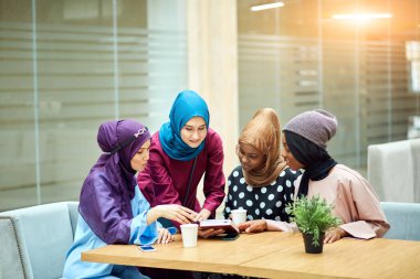 Kafede kitap okuyan neşeli genç Arap bayan öğrenciler..