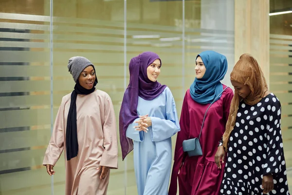 A group of four young muslim multiethnic girls chatting and walking together