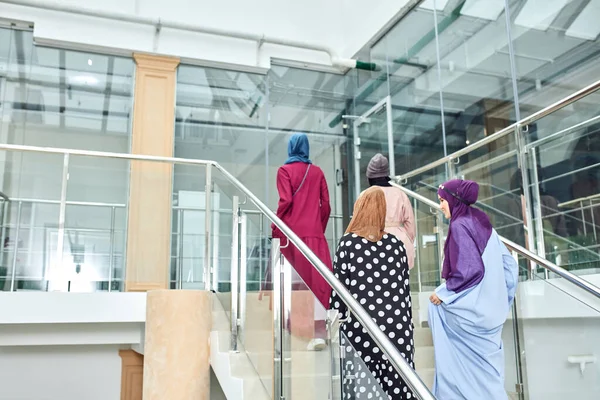 Group of four muslim girls walking at stairs of shopping mall