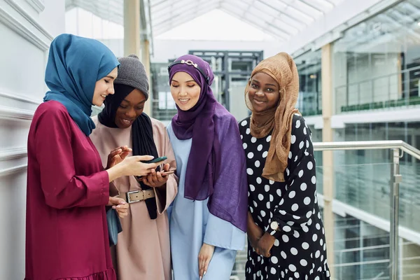 Gruppe islamischer Frauen unterschiedlicher ethnischer Zugehörigkeit schaut gemeinsam am Telefon zu — Stockfoto