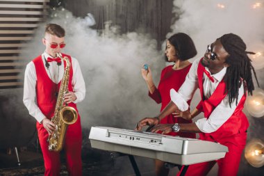 Rock 'n roll grubu dumanlı sahnede müzik yapıyor.