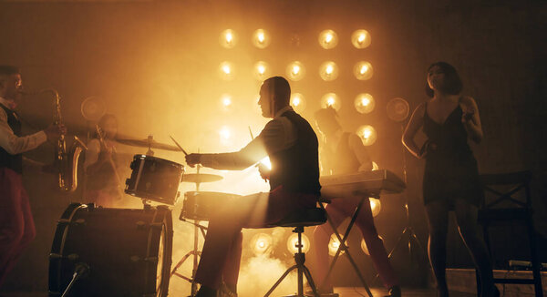 привлекательная женщина в черном платье и ее друзья в различных инструментальных сетях