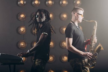 Kameraya poz veren saksafon ve klavyeli deneyimli sanatçılar