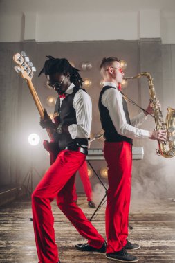 Kadın saksafon çalarken, beyaz adam akustik gitar çalıyor..