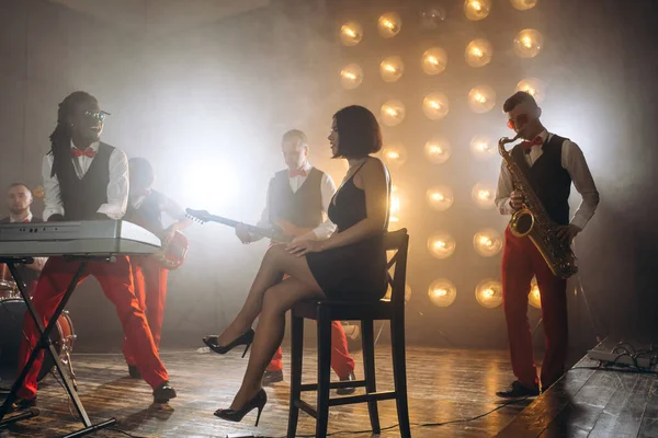 Elegante chica en vestido negro controlando la rehabilitación de una banda de jazz — Foto de Stock