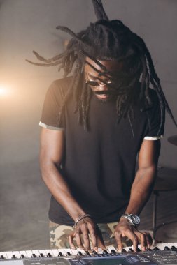 Genç ciddi adam sentezleyici çalmayı öğreniyor.