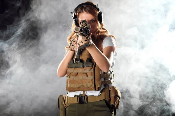 Havalı kadın nişancı otomatik bir saldırı tüfeği tutuyor ve düşmana nişan alıyor..