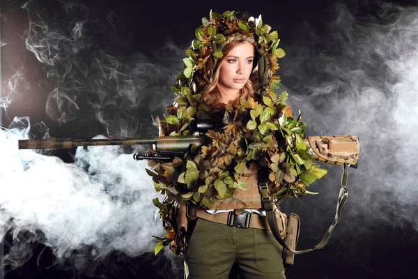 Mulher camuflada sniper em ghillie terno posando com rifle na noite nebulosa — Fotografia de Stock