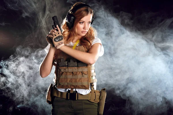 La mujer con armadura protectora sostiene el arma en las manos. Ejército, dedicación, tecnología. — Foto de Stock