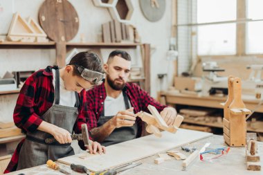 Baba ve oğlu ahşap bir atölyede birlikte çalışıp kuş evi inşa ediyorlar.