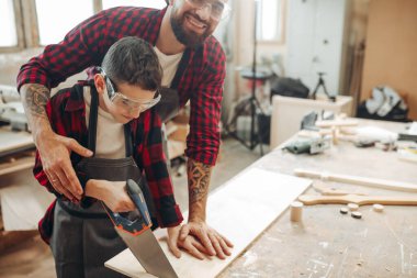 Babam ve oğlu atölyede çalışıyorlar. Tahta kesiyorlar. .