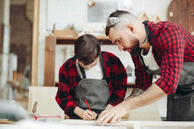 Cetvelli ve kalemli adamlar iş için tahta ölçüyorlar.